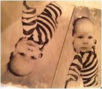 Een babyfoto op hout afgedrukt.